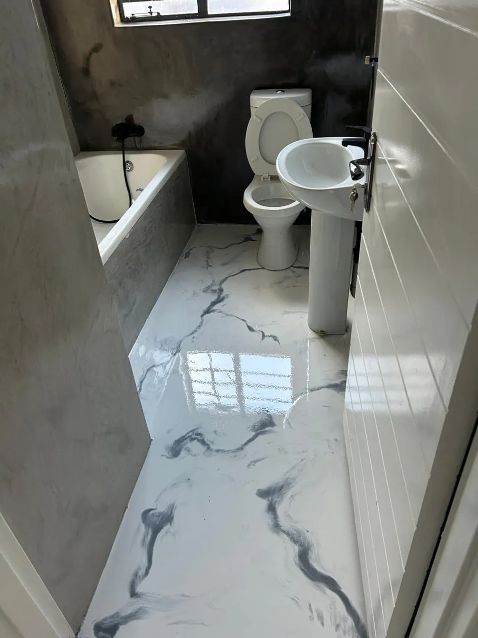 Bathroom with a white marble epoxy floor running past the bath, toilet and basin