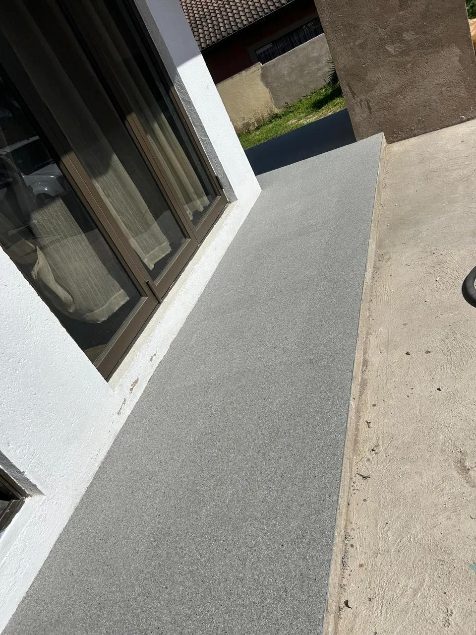Outdoor walkway along a house finished in a fine grey speckled coating